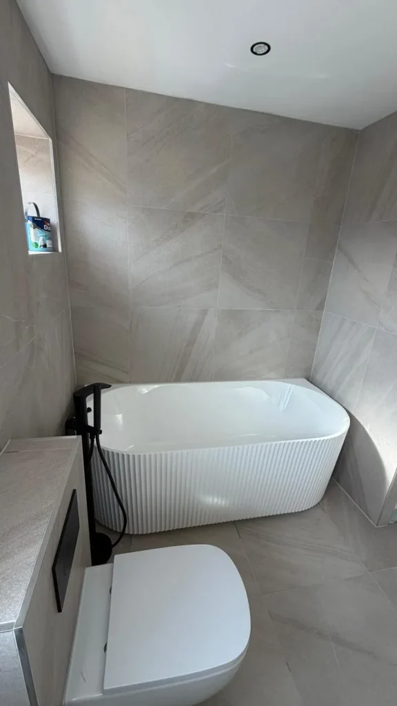 Fluted back-to-wall bath in a fully tiled bathroom