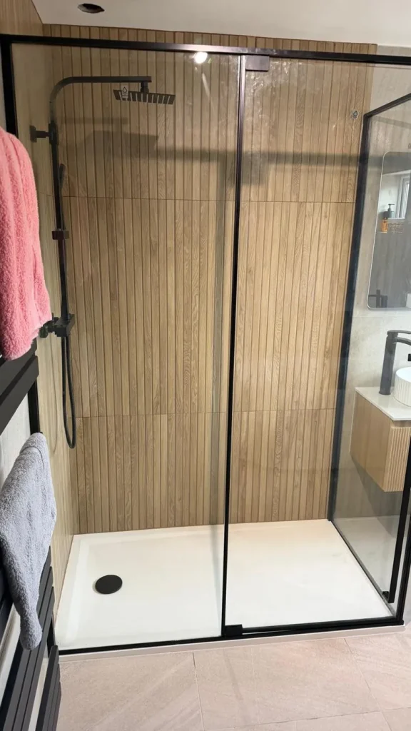 Walk-in shower with black rainfall shower and wood-effect wall tiles