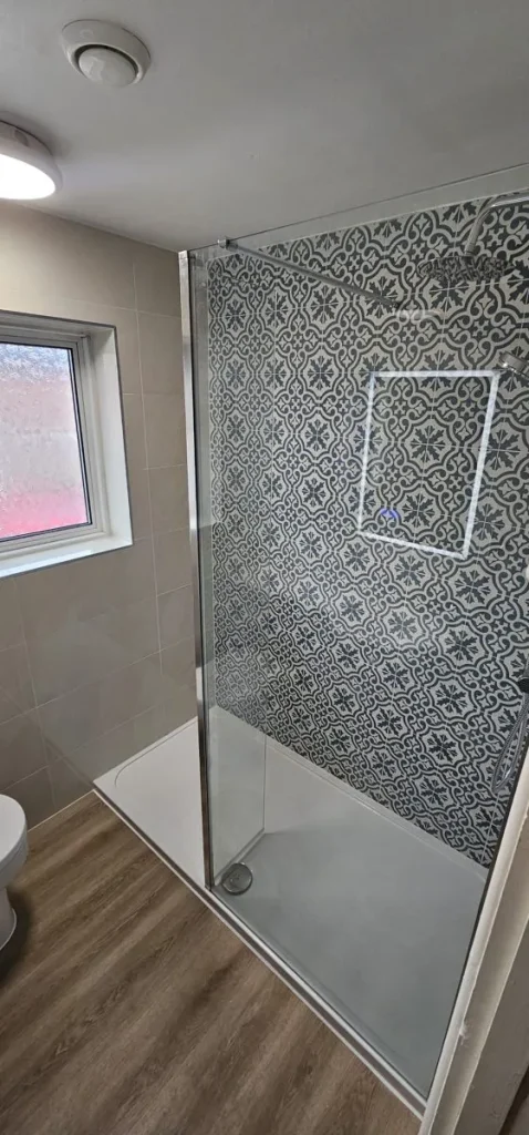 Walk-in shower with patterned blue feature tiles, illuminated niche and low-profile tray